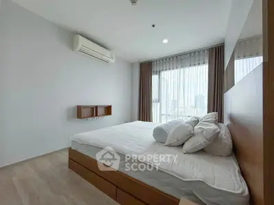 Spacious bedroom with large window and city view, featuring modern furnishings and air conditioning.