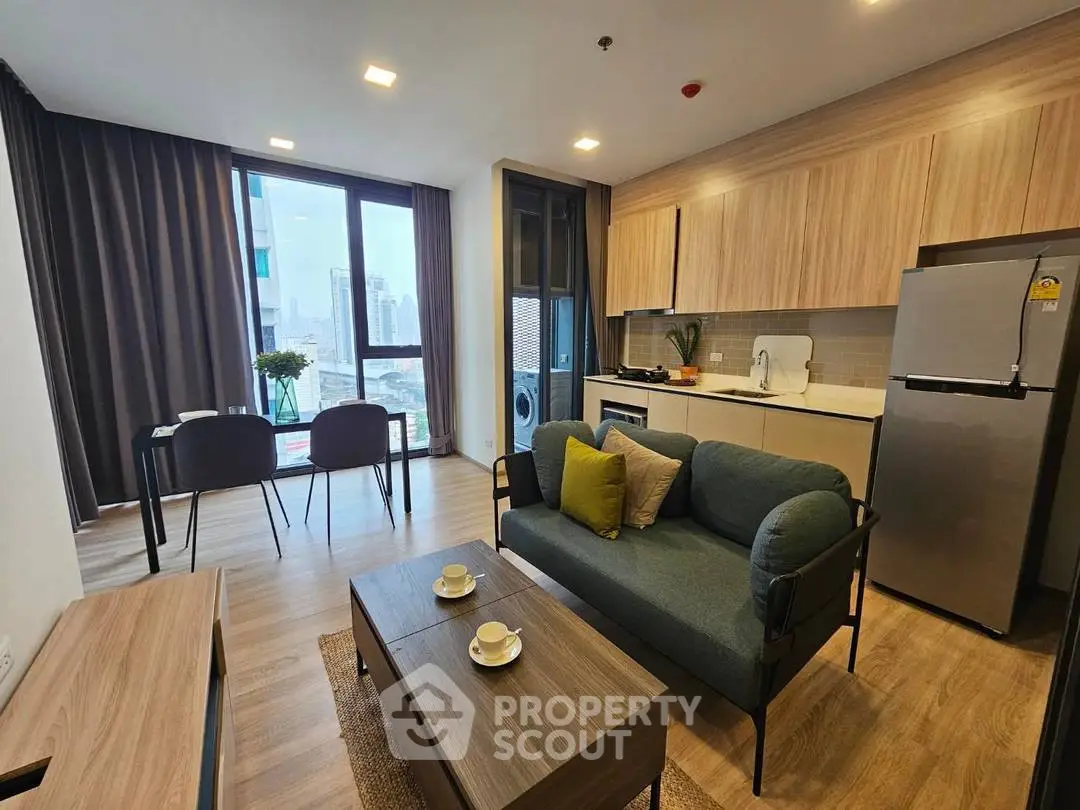 Modern living room with open kitchen, stylish furniture, and city view from large windows.