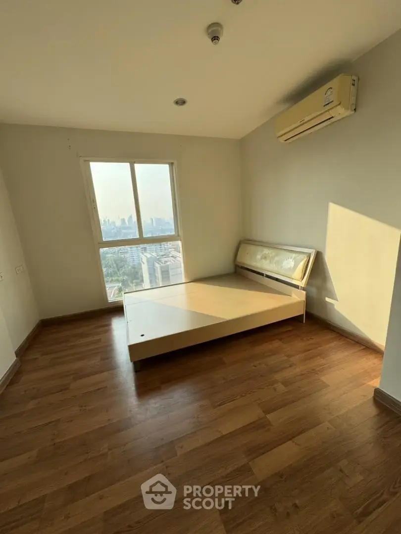 Spacious bedroom with wooden flooring and city view in modern apartment