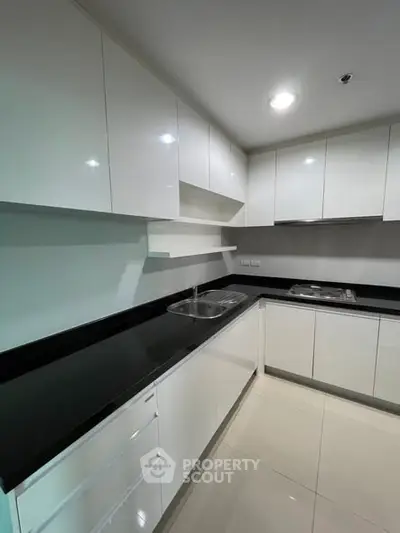 Modern kitchen with sleek white cabinets and black countertops