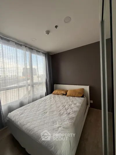 Cozy bedroom with large window and modern decor in a stylish apartment.