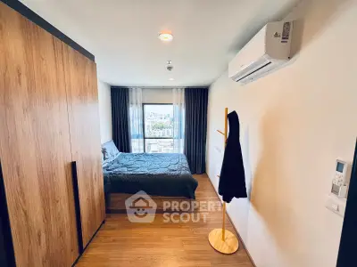 Modern bedroom with city view, featuring wooden flooring and sleek air conditioning unit.