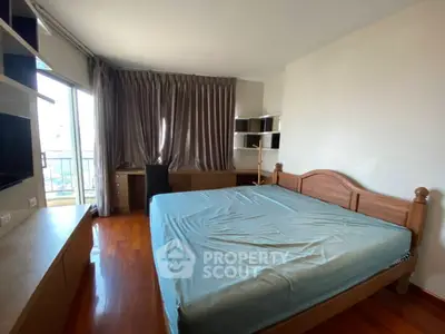Spacious bedroom with large window and wooden furniture
