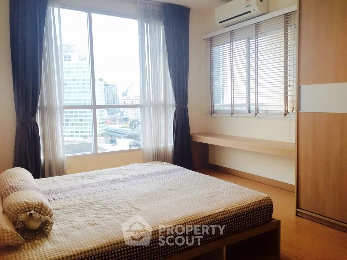 Bright bedroom with large windows and city view, featuring modern decor and ample natural light.