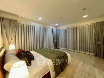 Spacious bedroom with elegant curtains and cozy lighting for a serene ambiance.