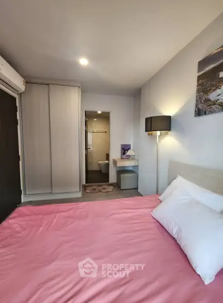 Cozy bedroom with pink bedding, modern wardrobe, and ensuite bathroom.