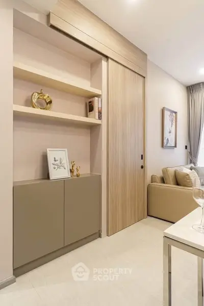 Modern living room with elegant decor and sliding wooden door, featuring a cozy beige sofa and stylish shelving.