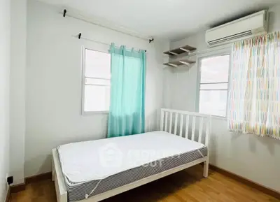 Bright bedroom with wooden flooring, air conditioning, and colorful curtains in a modern apartment.
