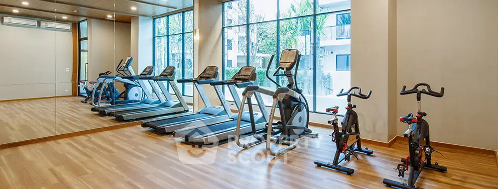 Modern gym with state-of-the-art equipment and large windows in a luxury residential building.