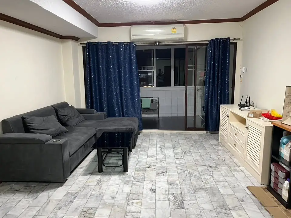 Spacious living room with modern gray sofa and marble flooring, featuring a balcony view.