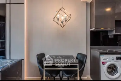 Modern dining area with stylish lighting and integrated washing machine in sleek kitchen.