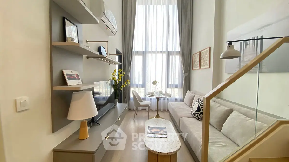 Modern living room with high ceilings, elegant decor, and large windows offering natural light.