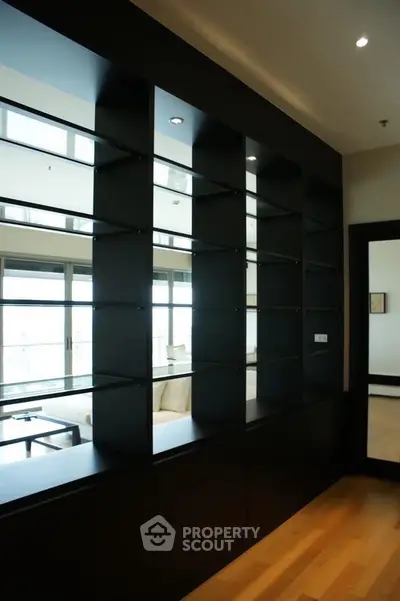 Spacious living room with modern shelving and large windows offering natural light.