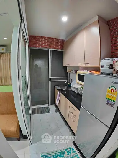 Compact kitchen with modern appliances and brick accent wall in cozy apartment