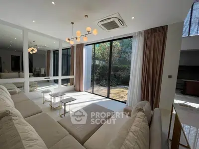 Luxurious living room with large windows and garden view, featuring modern lighting and plush seating.