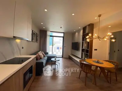 Modern living room with open kitchen, stylish lighting, and cozy seating area.