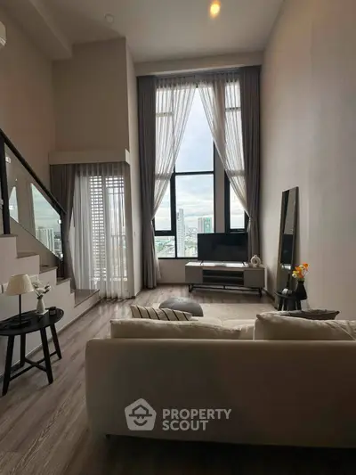 Spacious modern living room with high ceilings and large windows offering city views.