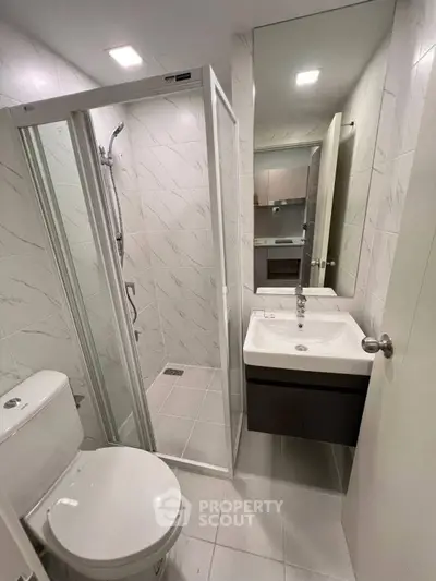 Modern bathroom with glass shower and sleek fixtures in contemporary apartment.