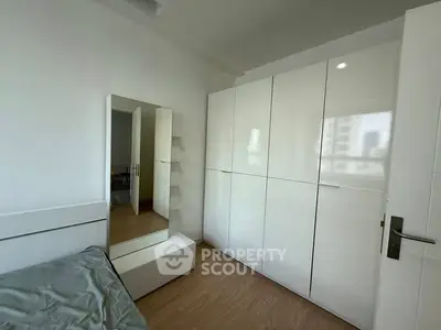 Modern bedroom with sleek white wardrobe and mirror, perfect for urban living.