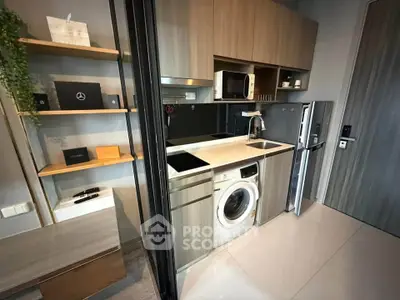 Modern compact kitchen with integrated appliances and sleek cabinetry in a stylish apartment.