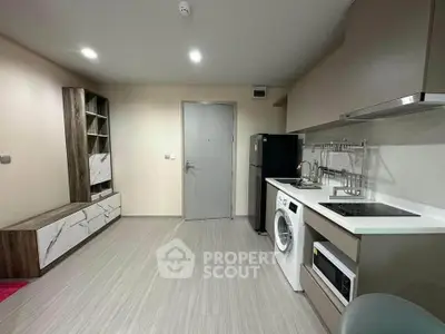 Modern kitchen with washing machine and sleek cabinetry in compact apartment.