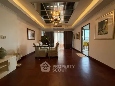 Spacious dining area with elegant chandelier and wooden flooring in a modern apartment.