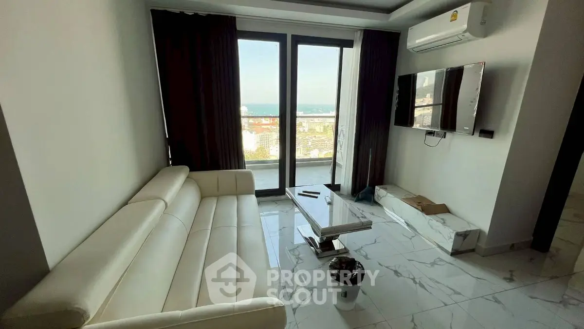 Modern living room with stunning city and sea view, featuring sleek white sofa and wall-mounted TV.