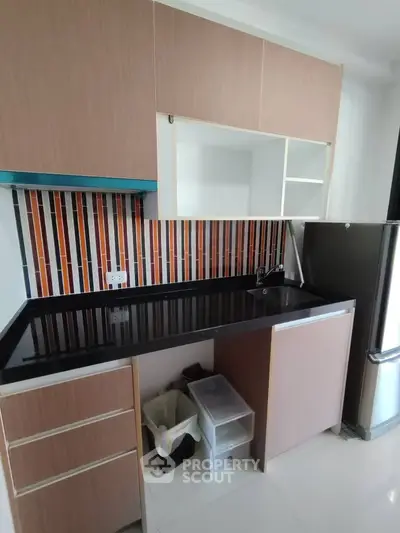 Modern kitchen with sleek cabinetry and colorful backsplash in a contemporary apartment.