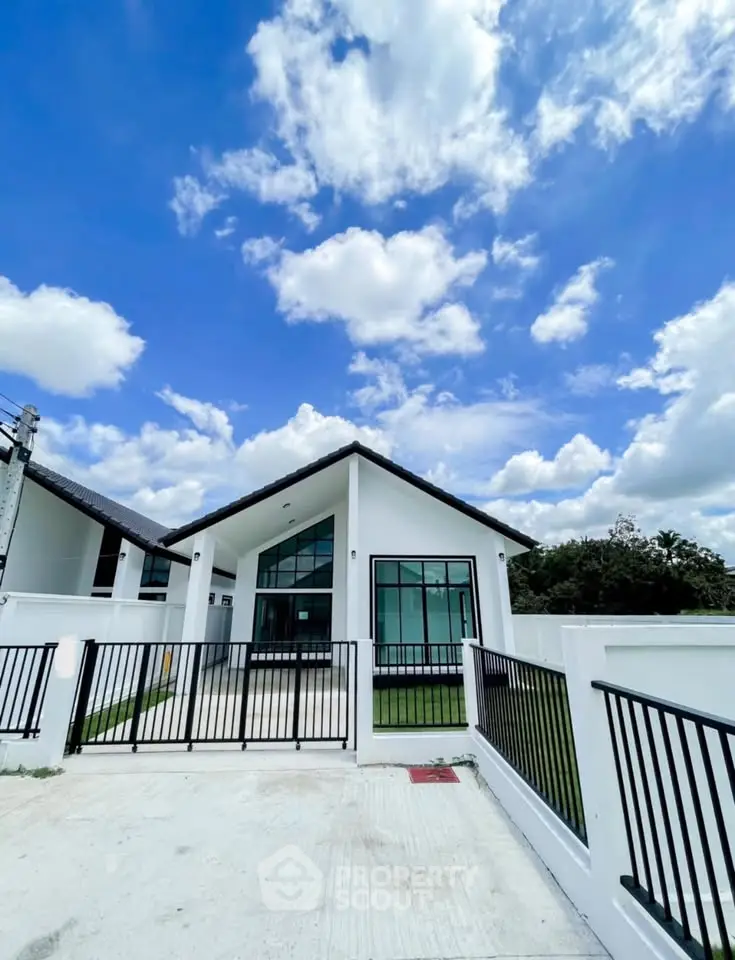 Modern single-story house with sleek design and spacious front yard under a bright blue sky.