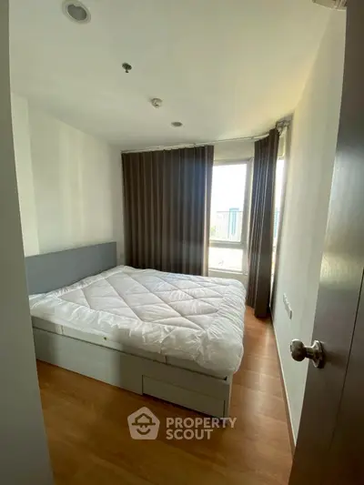 Cozy bedroom with large window and modern decor in urban apartment.