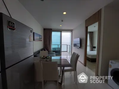 Modern beachfront condo with open-plan living space, sleek kitchen appliances, and a balcony offering stunning ocean views, perfect for a serene lifestyle.