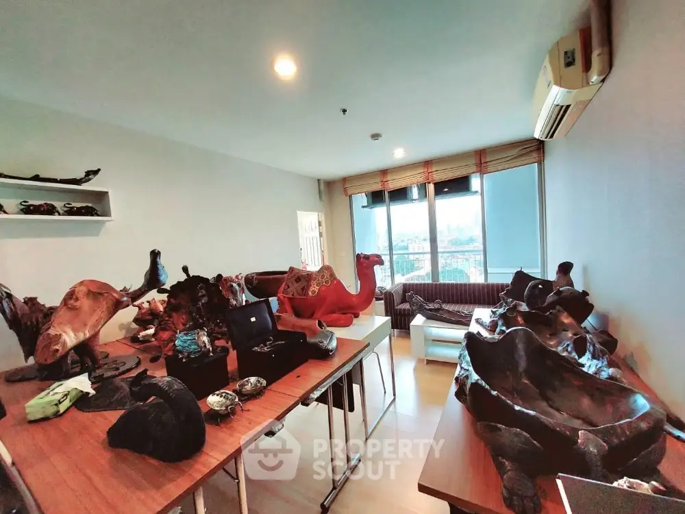 Spacious living room with unique wooden sculptures and large windows offering natural light.