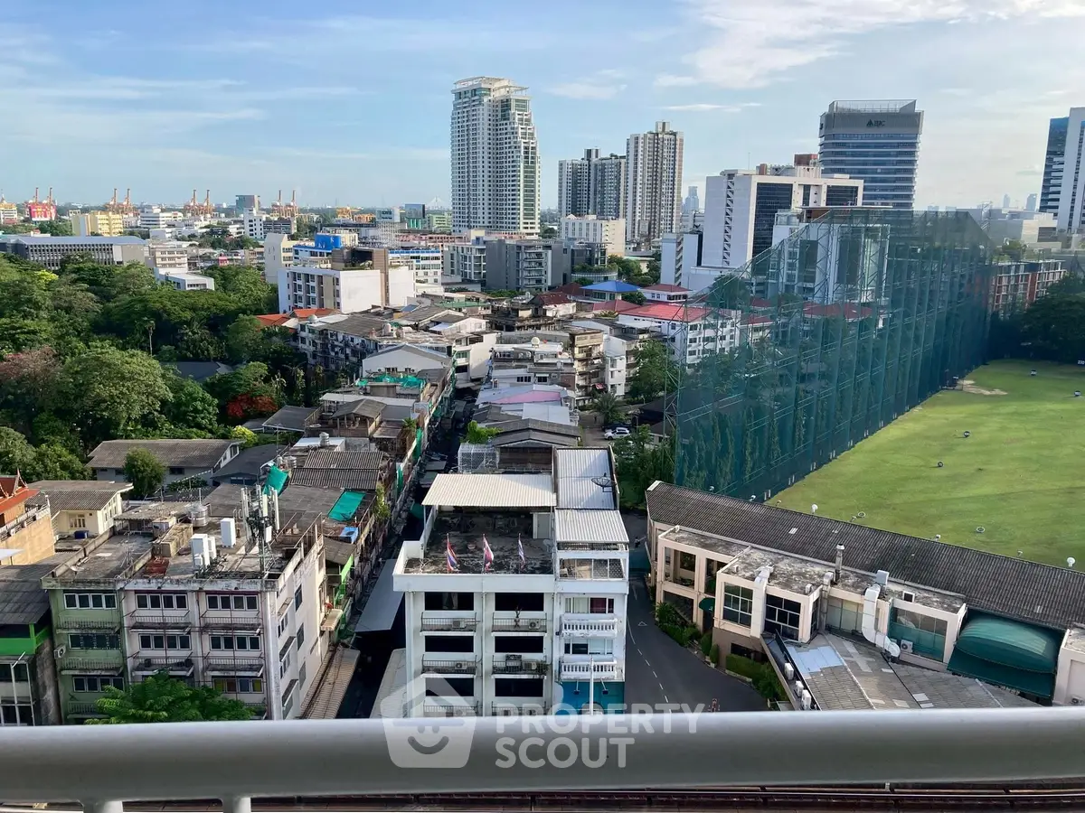 Stunning cityscape view from a high-rise balcony overlooking urban skyline and lush greenery.