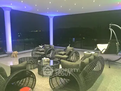 Luxurious outdoor seating area with modern wicker furniture and stunning night view.