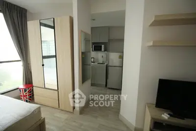 Modern studio apartment with sleek kitchen and cozy living area, featuring large windows and stylish decor.