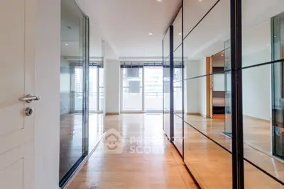 Spacious modern living room with floor-to-ceiling windows and mirrored walls, offering abundant natural light.