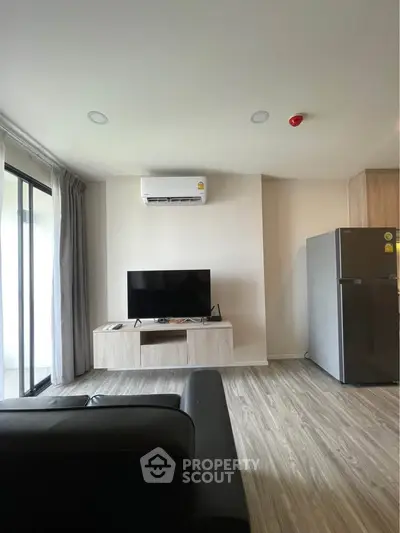 Modern living room with sleek TV setup and balcony access in stylish apartment.