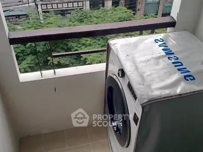 Compact balcony with washing machine and greenery view, ideal for urban living.