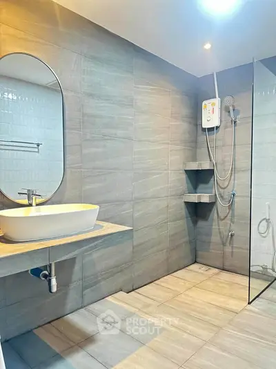 Modern bathroom with sleek design, featuring a glass shower enclosure and stylish oval mirror.