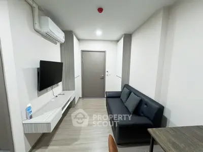 Modern living room with sleek furniture and mounted TV in a compact apartment.