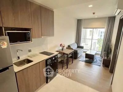 Modern open-layout kitchen and living room with balcony view in stylish apartment.