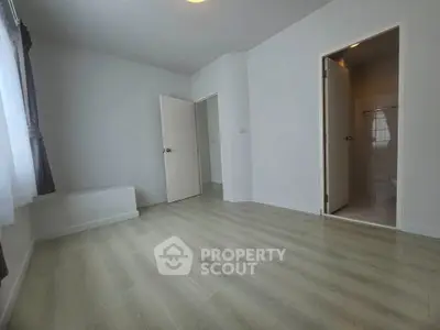Spacious empty room with light wood flooring and natural light, ideal for customization.