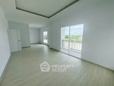 Spacious empty living room with large windows and balcony access, perfect for customization.