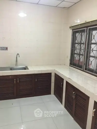Spacious kitchen with closed layout and modern sink in a tiled interior.