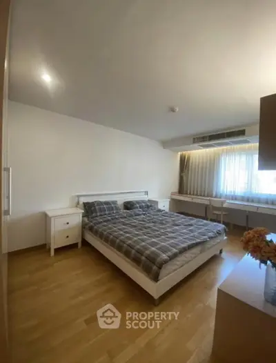 Spacious bedroom with wooden flooring and modern furnishings