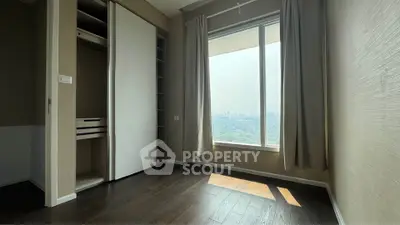 Spacious bedroom with large window offering stunning city view and ample natural light.