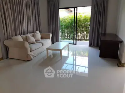 Spacious living room with modern sofa and large window overlooking greenery