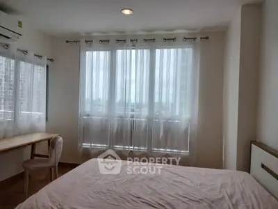 Bright bedroom with large windows offering a stunning city view, featuring a cozy bed and elegant decor.