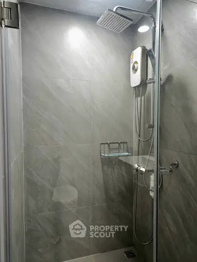 Modern bathroom with sleek shower and gray tiles, featuring a rain showerhead and glass enclosure.