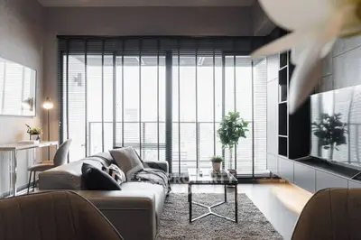 Modern living room with sleek furniture and large windows offering city views.
